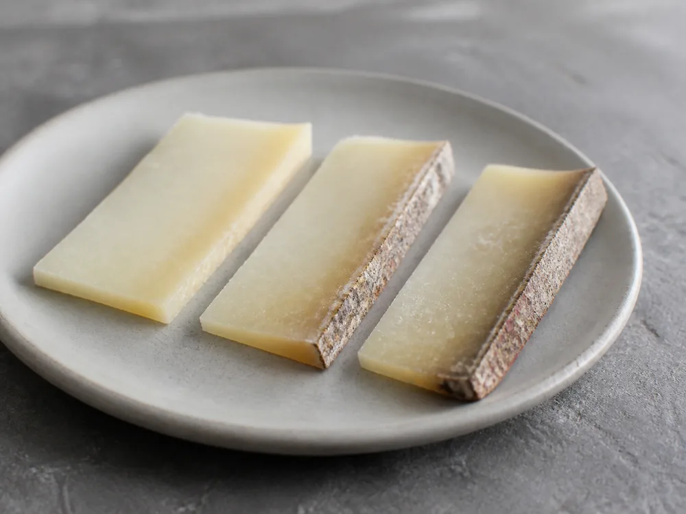 Thin Belloc-style slices showing center paste and mottled natural rind - Abbaye de Belloc | KnowTheCheese