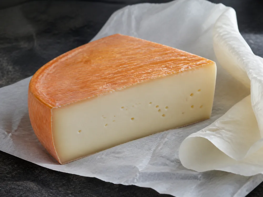 Clean orange rind and springy cut face on a Timadeuc-style wedge - Abbaye de Timadeuc | KnowTheCheese