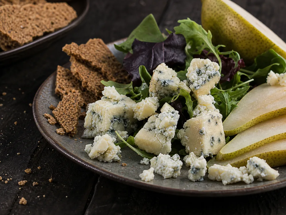 Small Adelost-style blue cheese crumbles over salad leaves with rye crispbread - Adelost | KnowTheCheese