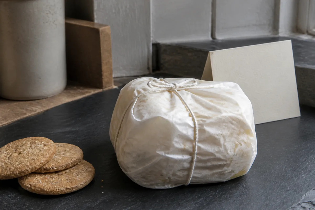 Rock-shaped cheese wrapped in waxed paper and tied with string on a slate counter - Ailsa Craig | KnowTheCheese