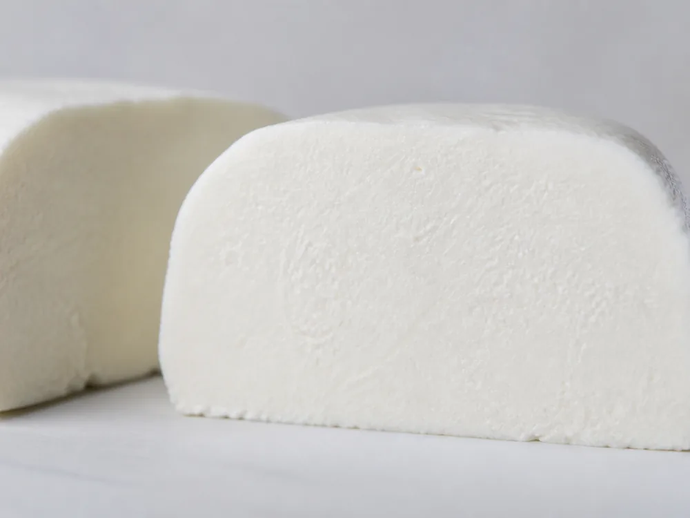 Cut face showing bright white paste running to the surface with no rind line - Ailsa Craig | KnowTheCheese