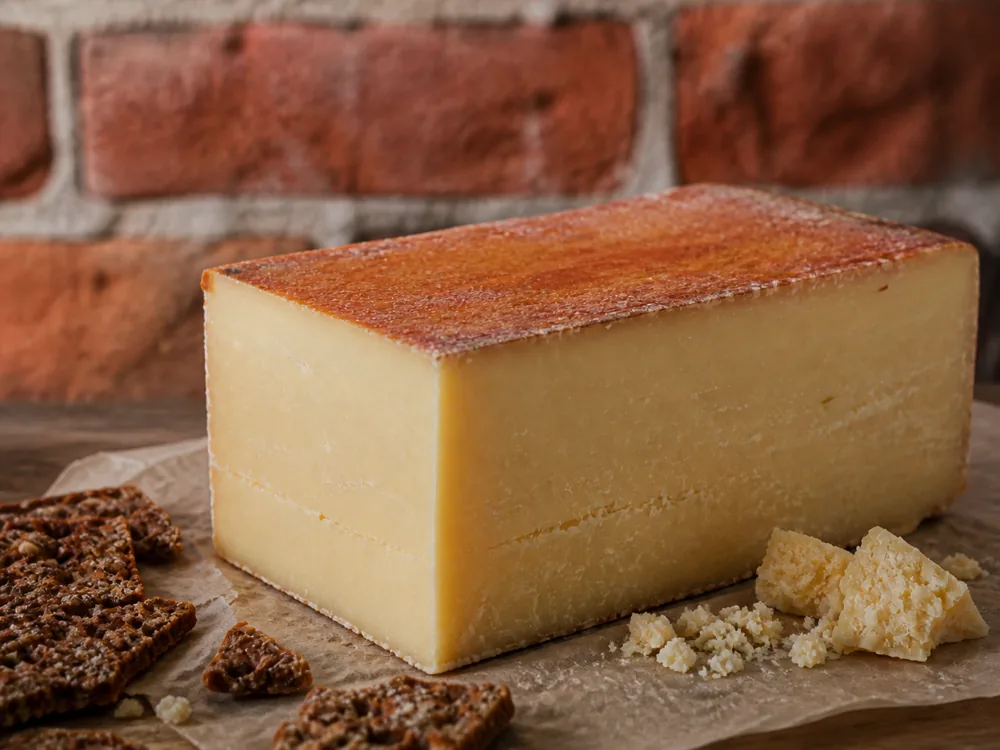 Brick-shaped Almnäs Tegel-style cheese wedge with reddish rind and dense paste - Almnäs Tegel | KnowTheCheese