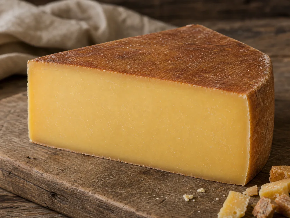 Alpha Tolman-style wedge with brushed rind and dense golden paste - Alpha Tolman | KnowTheCheese