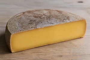 Half wheel of alpine cheese with a dry brown natural rind and a deep straw gold close paste - Alta Badia | KnowTheCheese