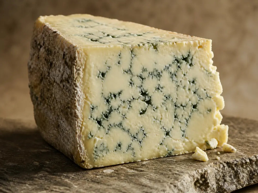 Blue cheese wedge with creamy paste and blue veins on stone board - AmaBlu | KnowTheCheese