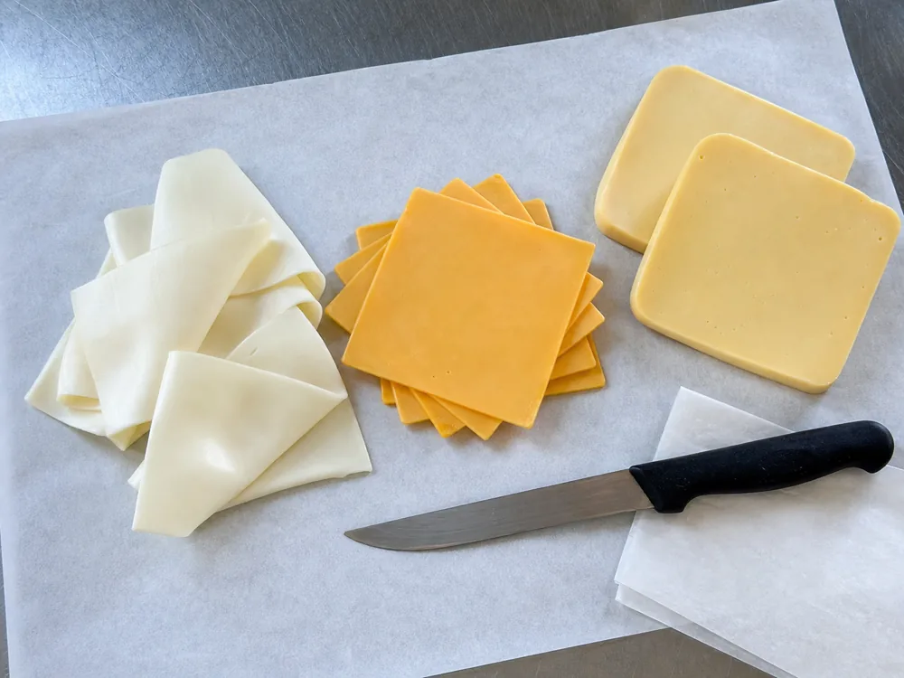 White yellow and thick-cut American cheese slices on deli paper - American cheese | KnowTheCheese