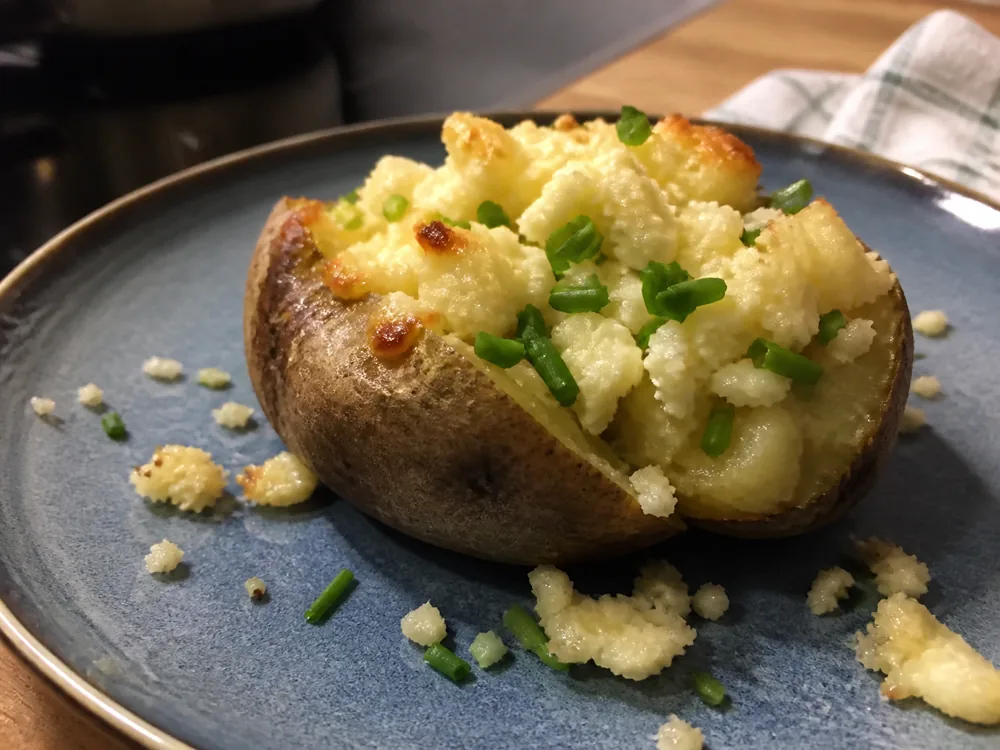 Crumbly Anster-style cheese softening over a baked potato - Anster | KnowTheCheese