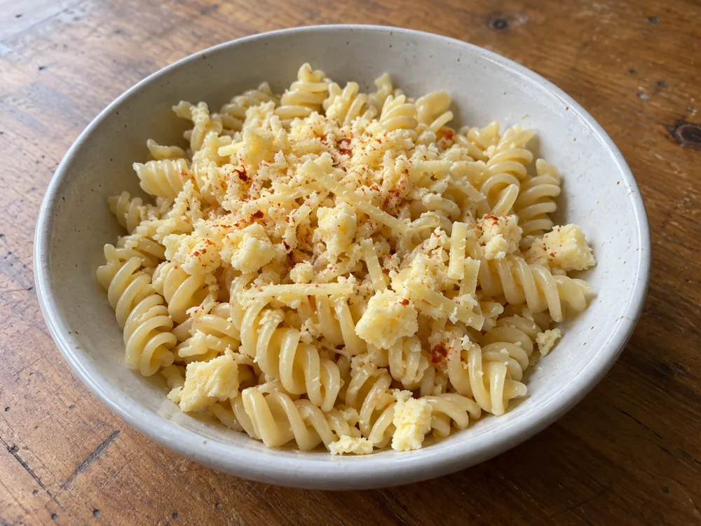 Cooked pasta topped with crumbled and grated smoky cheese - Applewood