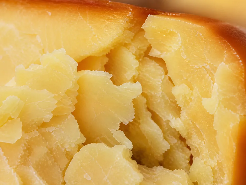 Macro of a crumbled pale gold face with a darker smoked band along the outer edge - Auld Reekie | KnowTheCheese