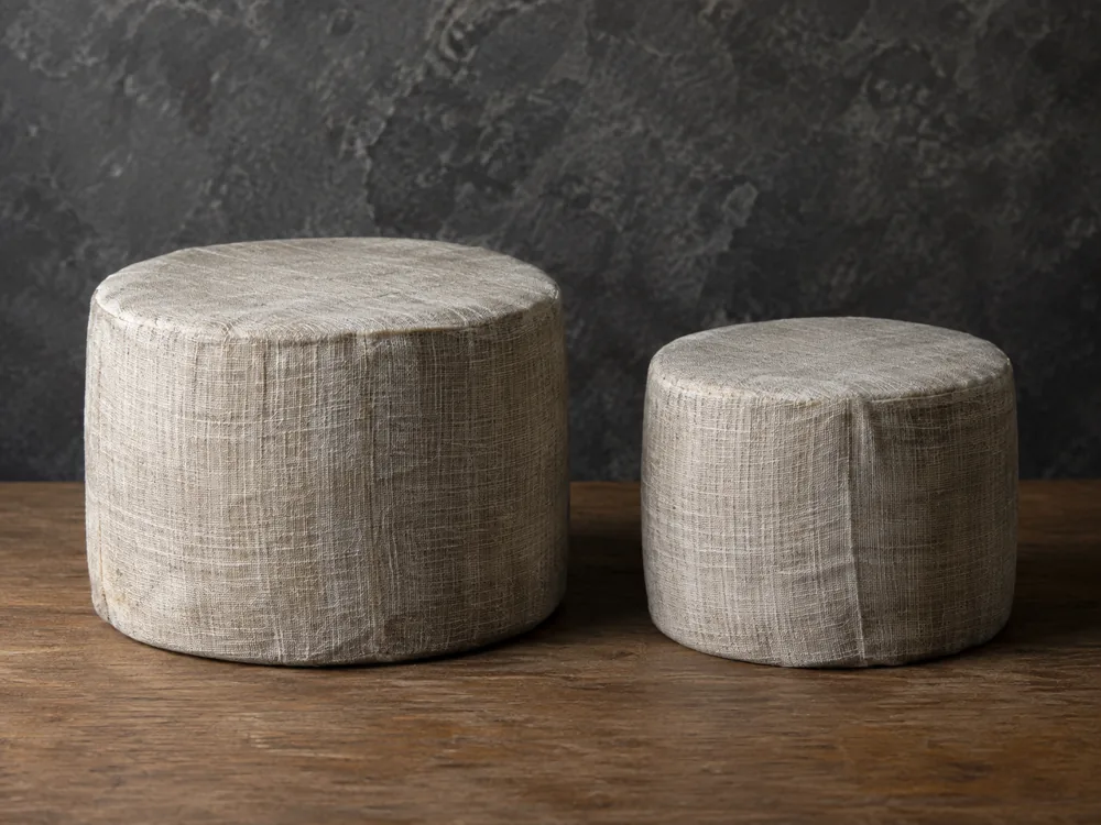 Two cloth-wrapped cheese wheels, one larger than the other, side by side - Avonlea Clothbound Cheddar | KnowTheCheese