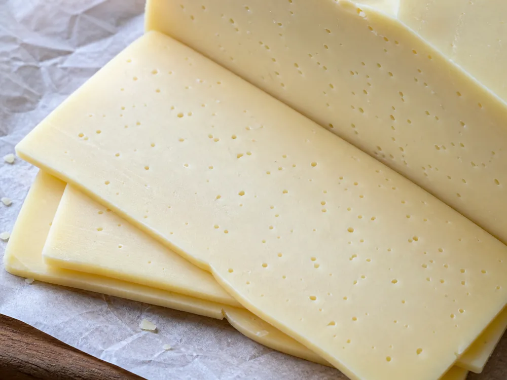 Baby Swiss slices showing small close-set eyes - Baby Swiss | KnowTheCheese