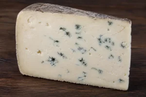 Thick wedge of dense pale blue cheese with mould in irregular patches and a thin natural rind - Barden Blue | KnowTheCheese