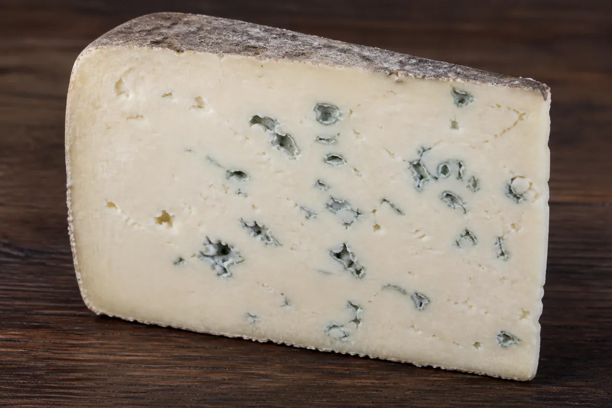 Thick wedge of dense pale blue cheese with mould in irregular patches and a thin natural rind - Barden Blue | KnowTheCheese