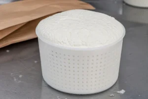 Fresh white cheese filling the perforated basket it drained in - Basket Cheese | KnowTheCheese