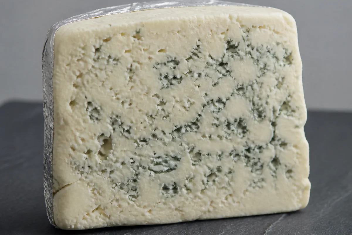 Wedge of pale ivory sheep milk blue with fine blue-green veining on slate - Beenleigh Blue | KnowTheCheese