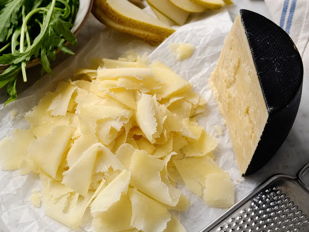 Thin Bella Lodi style cheese flakes beside a black-rind wedge - Bella Lodi cheese | KnowTheCheese
