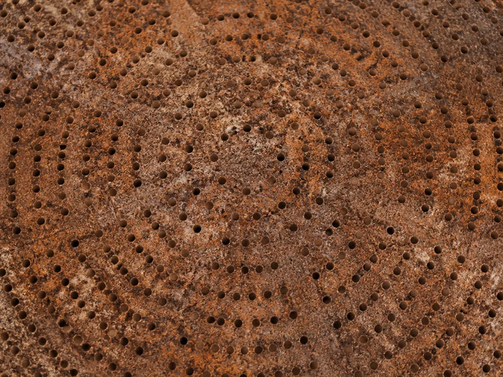 Overhead detail of colander perforations and ridges pressed into a rusty natural rind - Berkswell | KnowTheCheese