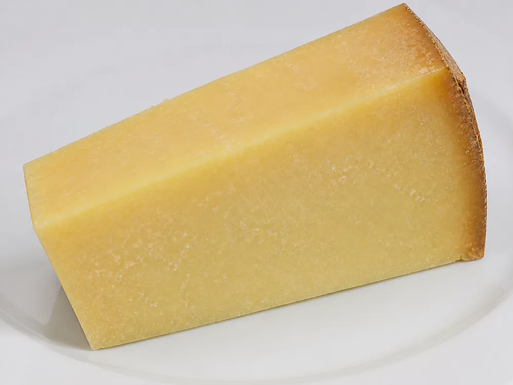 Cut wedge showing dense pale butter-coloured paste with a rusty rind edge - Berkswell | KnowTheCheese