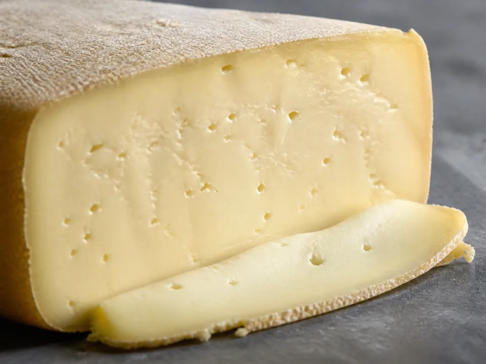 Soft pale Bianco cheese slice beside its natural rind - Bergader Bianco | KnowTheCheese