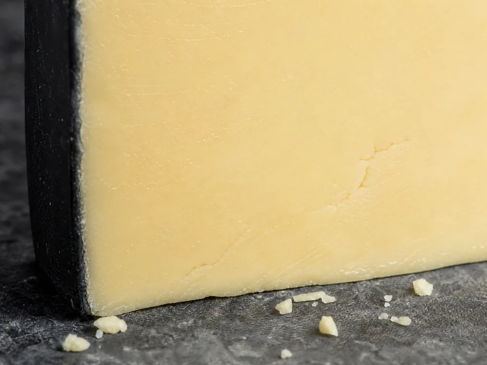 Creamy ivory Cheddar beside a thin black wax edge - Black Bomber Cheddar | KnowTheCheese