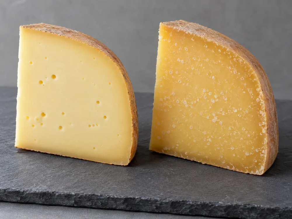 Two cheese wedges side by side, the left smooth and supple with a few small holes and the right firmer and drier with small white crystal specks - Boerenkaas | KnowTheCheese