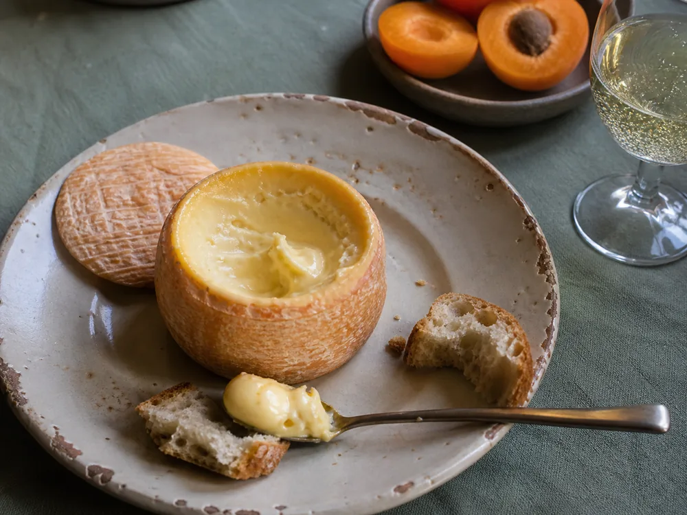 Ripe washed-rind Bossa spread on baguette beside stone fruit - Bossa cheese | KnowTheCheese