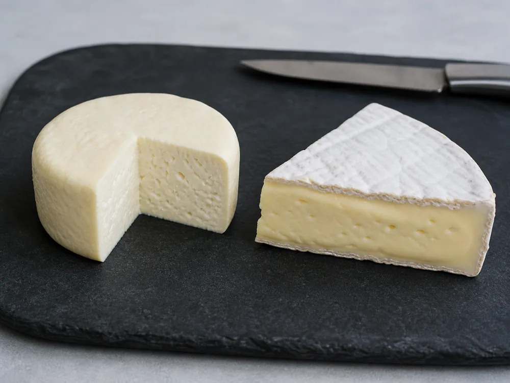 Rindless springy Breakfast Cheese beside ripe bloomy rind Brie