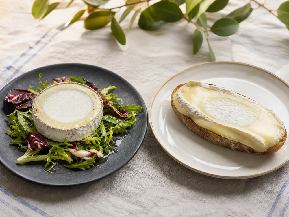 Young Bucheron on bitter leaves beside ripe Bucheron spread on toast - Bucheron cheese | KnowTheCheese