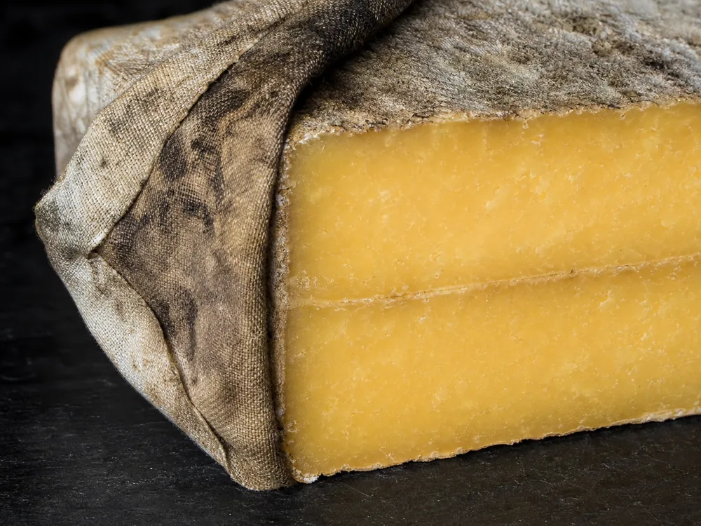 Peeled cloth showing the dry natural rind and golden cheddar paste beneath | KnowTheCheese