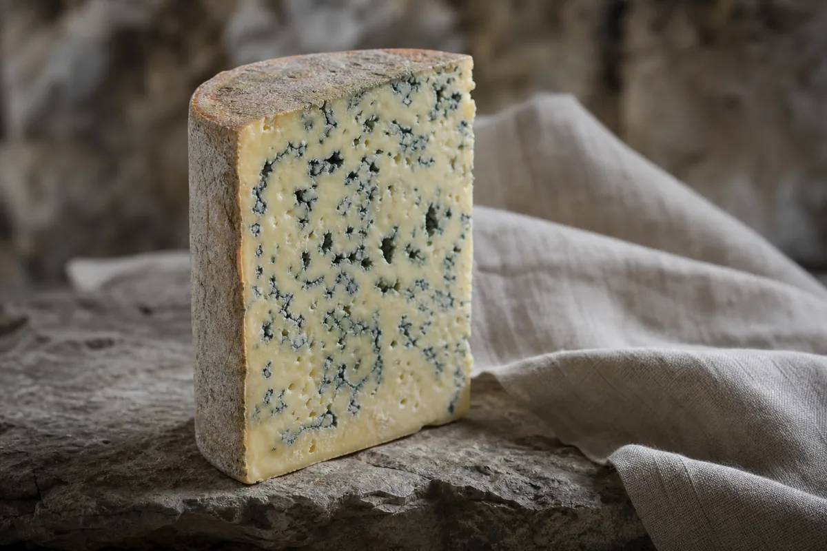 Tall wedge of densely veined Cabrales-style blue cheese with a thin natural rind - Cabrales