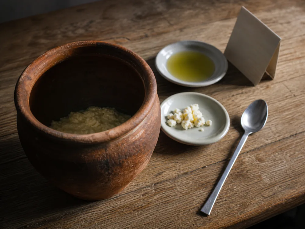 Fresh cheese pieces and olive oil beside a maintained pot of fermented cheese paste | KnowTheCheese