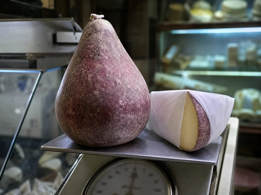 Pear-shaped Caciobarricato on a deli scale with its mottled wine-treated rind | KnowTheCheese
