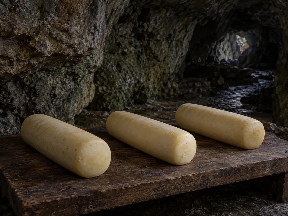 Drum-shaped cheeses resting in a natural stone cave - Caciobufala | KnowTheCheese