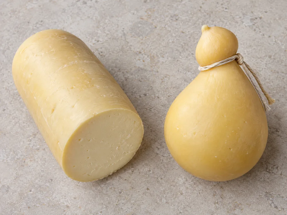 Long drum-shaped pale yellow cheese beside a tear-drop shaped cheese tied with string - Caciobufala | KnowTheCheese