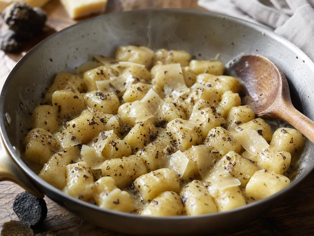 Caciotta al Tartufo shavings softening over hot potato gnocchi off the heat | KnowTheCheese