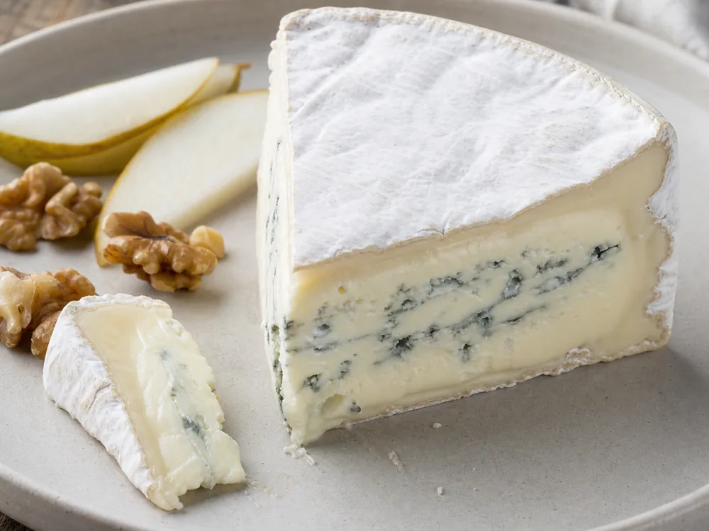 Cambozola wedge showing creamy bloomy rind and gentle blue veining - Cambozola cheese | KnowTheCheese