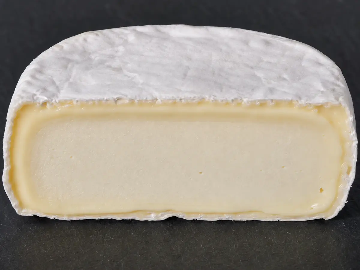 Cut oval cheese with a softened layer beneath its white rind - Caprice des Dieux cheese | KnowTheCheese