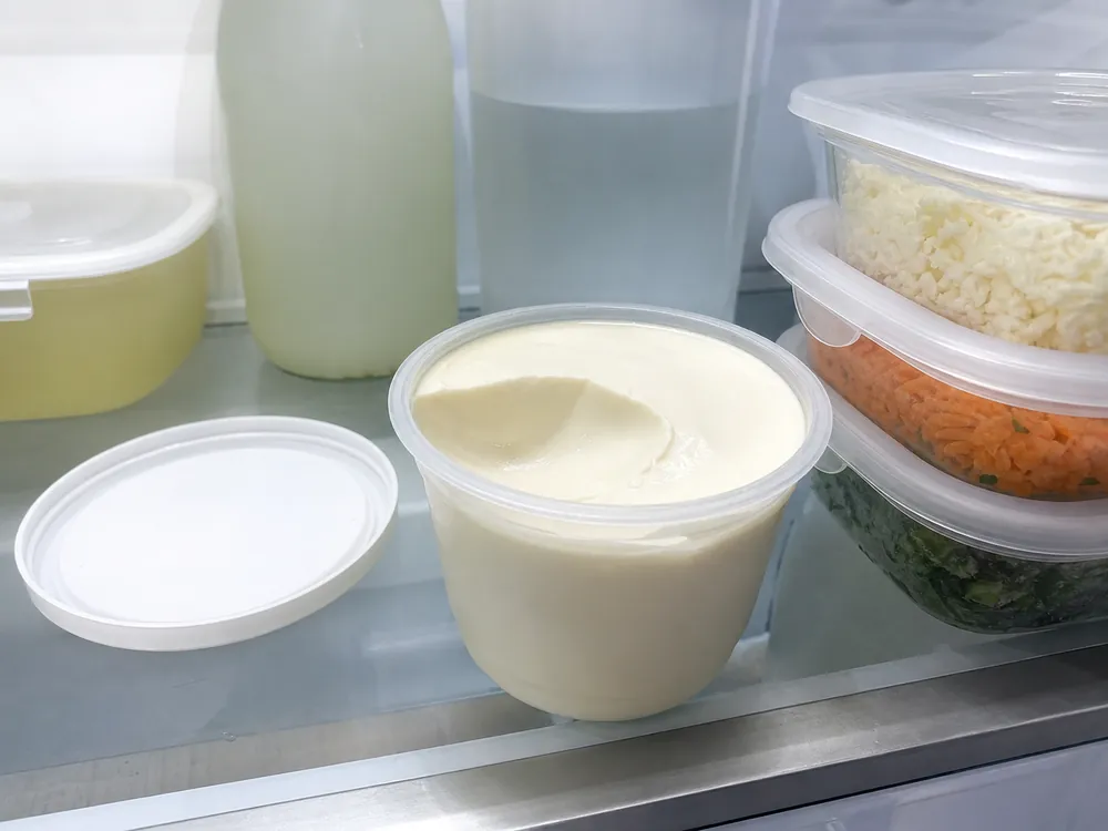 Opened tub of thick Brazilian requeijao stored on a refrigerator shelf | KnowTheCheese