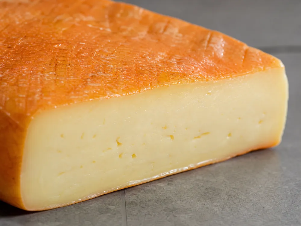 Thin orange washed rind meeting pale flexible cheese paste | KnowTheCheese