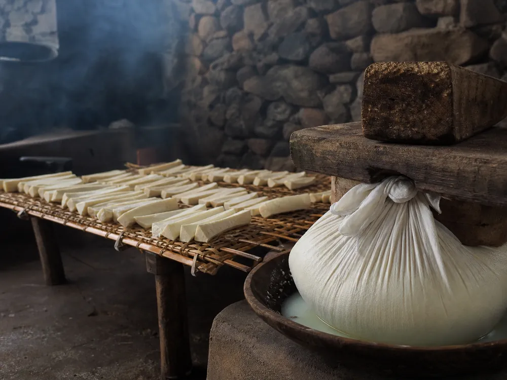 Acid-set curd draining under weight beside chhurpi strips drying on a rack | KnowTheCheese