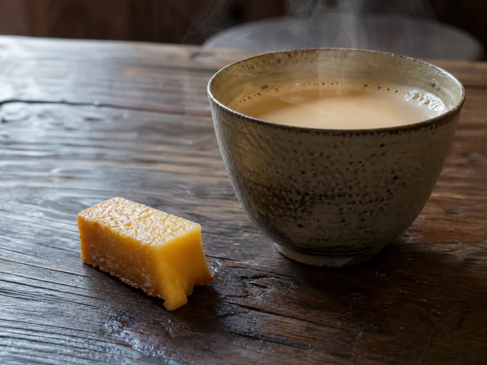 Small hard chhurpi piece with a softened edge beside hot tea | KnowTheCheese