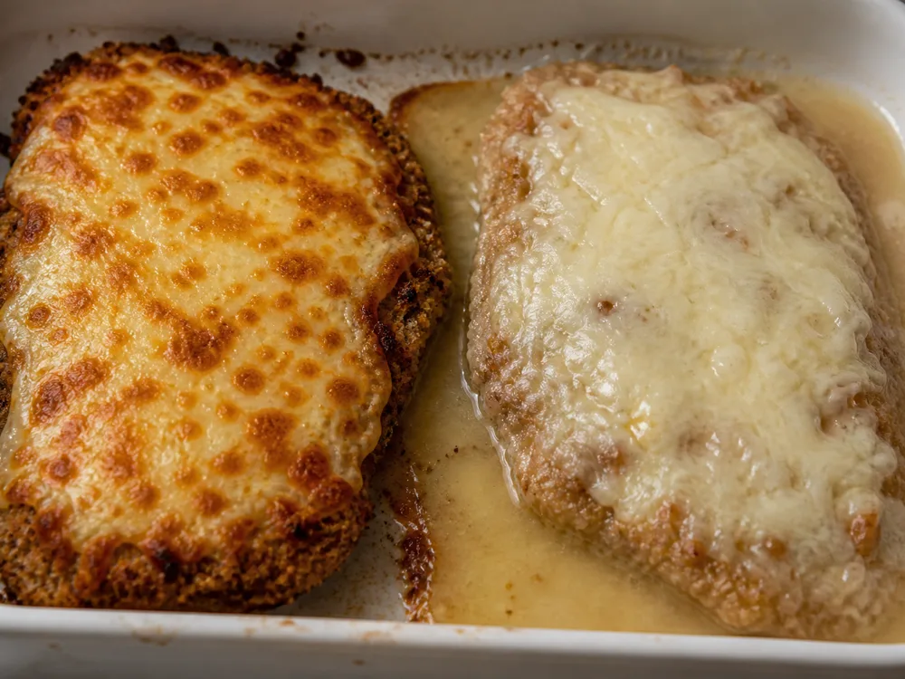 Two baked cutlets side by side, one with tight browned cheese and one sitting in released water - chicken parmesan | KnowTheCheese