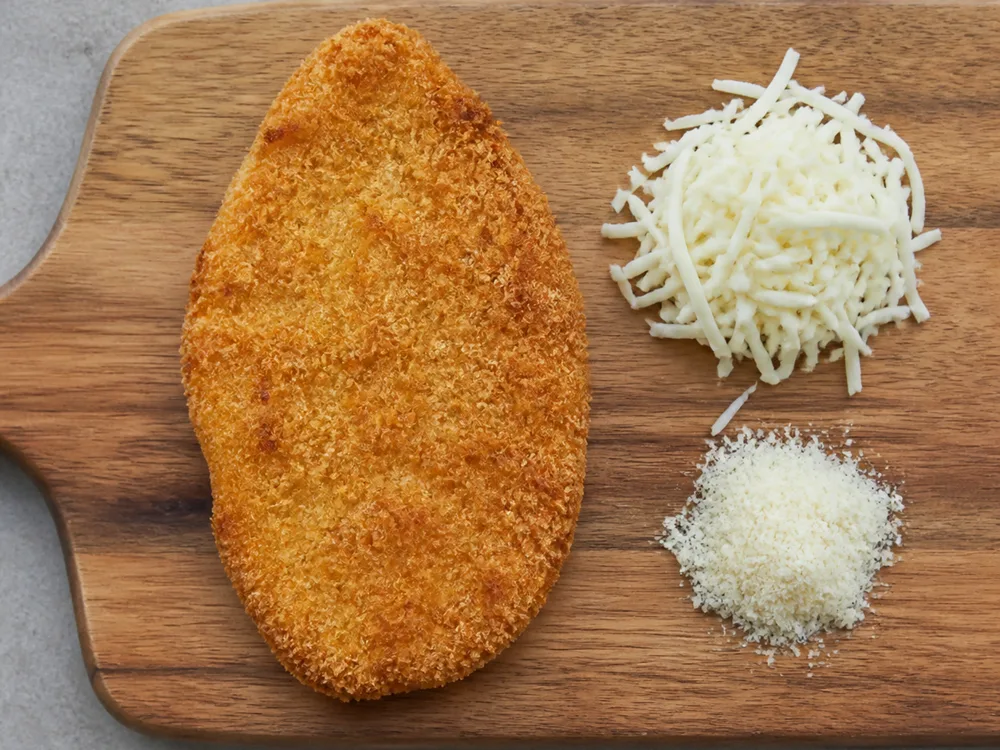 One breaded cutlet beside a measured handful of shredded mozzarella and grated hard cheese - chicken parmesan | KnowTheCheese