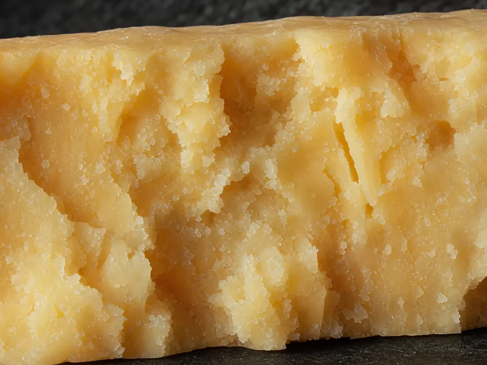 Tiny white crystals and crumbly fissures in broken Coastal Cheddar - Coastal Cheddar | KnowTheCheese