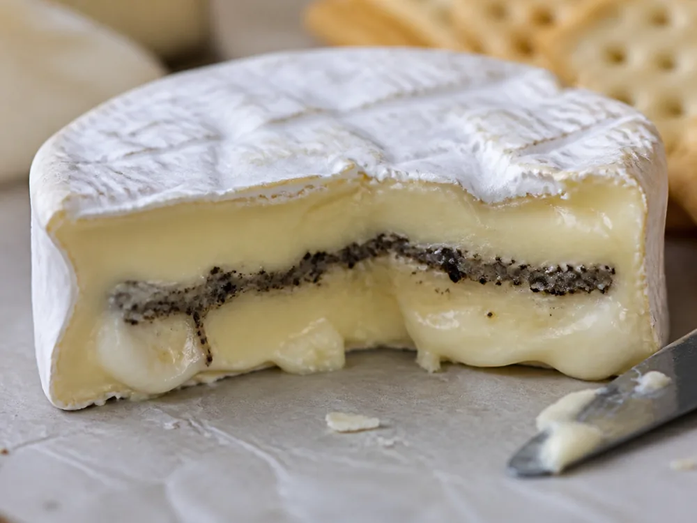 Cut bloomy rind cheese with creamy paste and truffle layer - College White With Truffles | KnowTheCheese