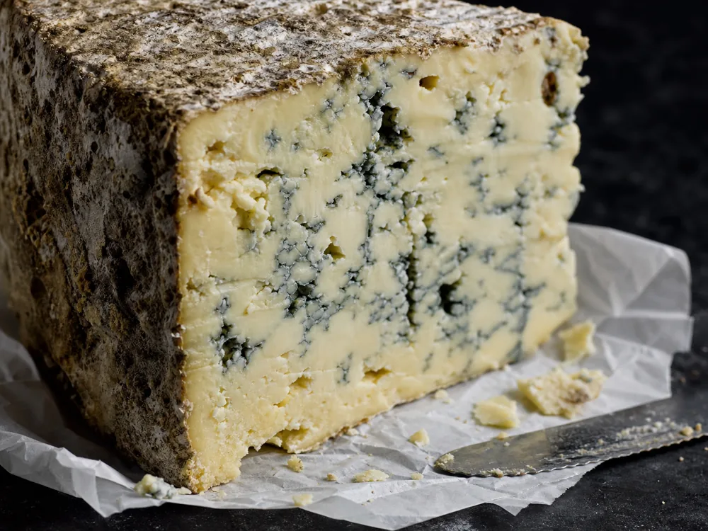 Blue Stilton cut face with rind open crumb and blue green veins - Colston Bassett Stilton | KnowTheCheese