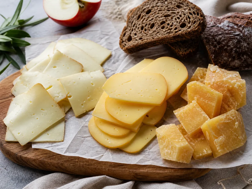 Young Gouda slices, aged Gouda chunks, and Havarti slices in an age-range lineup - Havarti vs Gouda | KnowTheCheese