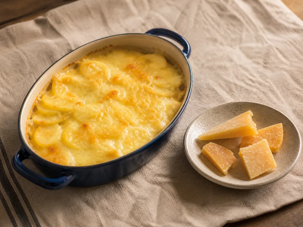 Young Comte melted on potato gratin beside aged Comte shards - Comte | KnowTheCheese