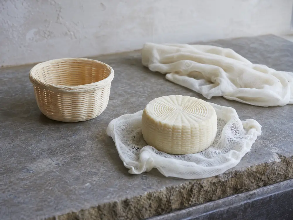 Basket mold draining cloth and a newly formed ridged sheep milk wheel - Pecorino Crotonese | KnowTheCheese