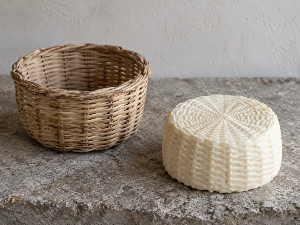 Empty basket mold beside a formed pale sheep milk cheese with a basket pattern - Pecorino Crotonese | KnowTheCheese